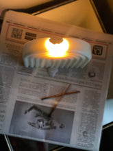 Load image into Gallery viewer, Lit sculptural white candle with arch design on newspaper with incense.